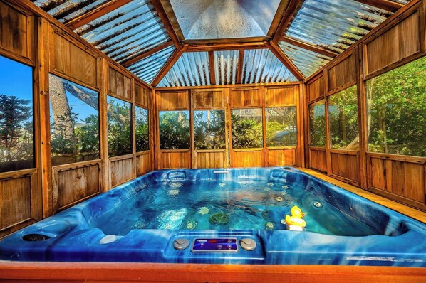 A hot tub with a control panel, surrounded by wooden walls and large windows.