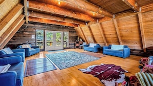 A cozy log cabin interior with a high ceiling, wooden beams, and a rustic aesthetic.