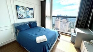 A hotel room with a large bed, a painting on the wall, a view of the city through the window, and a desk with a lamp. - Nanahousing-Nice Apartment near Korea Town & Chinese Area (Hanoi)