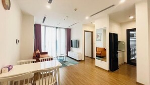 A modern living room with a dining area, a TV, and a kitchen area. - Nanahousing-Nice Apartment near Korea Town & Chinese Area (Hanoi)