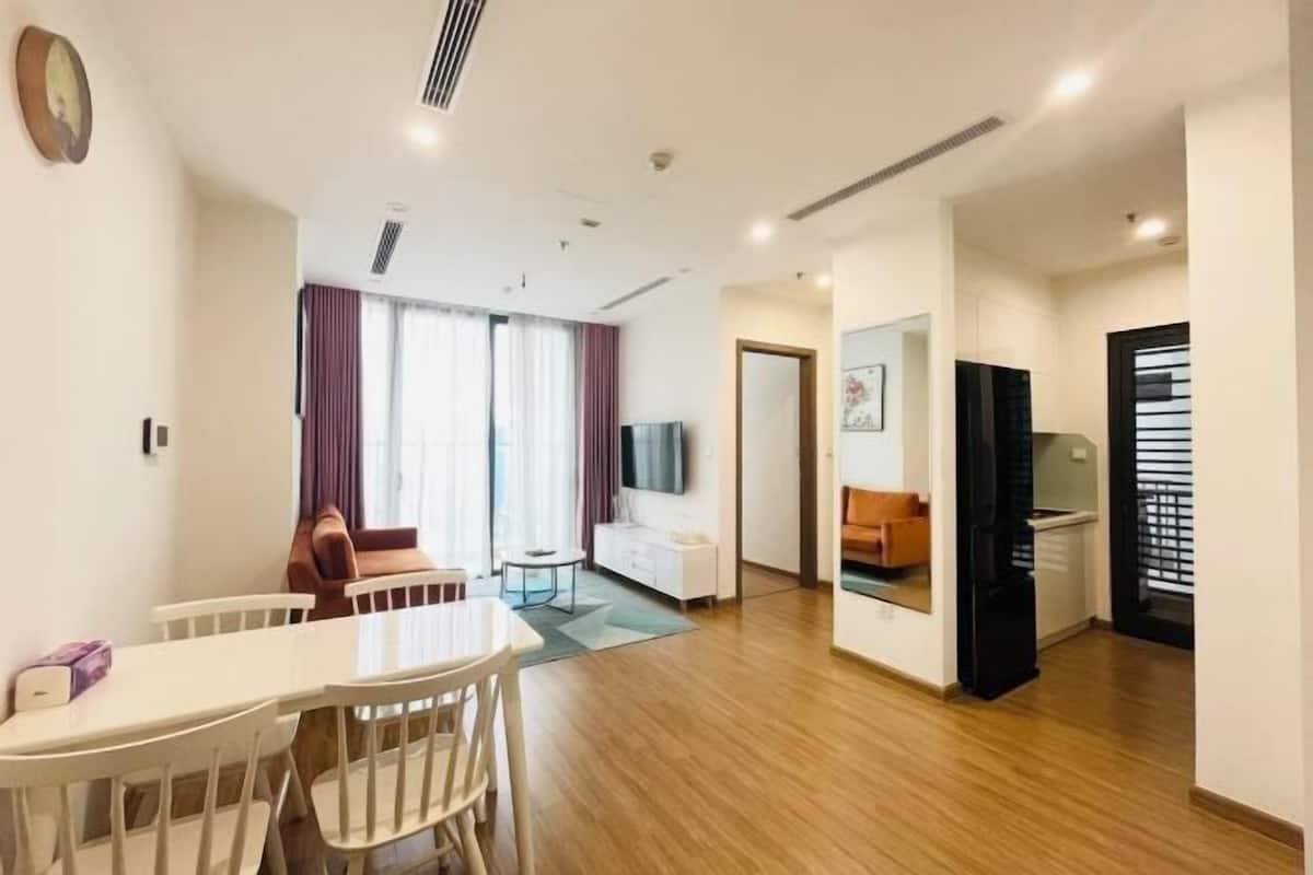 Uma sala de estar moderna com área de jantar, televisão e cozinha.