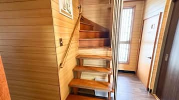 A wooden staircase with a handrail, leading to a door with a sign.