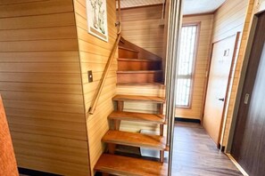 A wooden staircase with a handrail, leading to a door with a sign. - HAGINOTCHI (Shiraoi District)