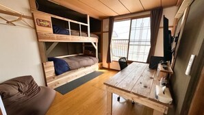 A compact room with a bunk bed, a small desk, and a seating area. - HAGINOTCHI (Shiraoi District)