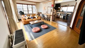 A living room with a sofa, a coffee table, and a radiator. There is a dining area with chairs and a table. - HAGINOTCHI (Shiraoi District)