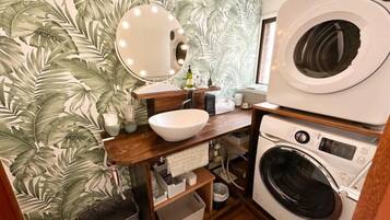 A compact bathroom with a sink, mirror, and washing machine.