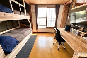 Una habitación con literas, un escritorio con computadora y una ventana.