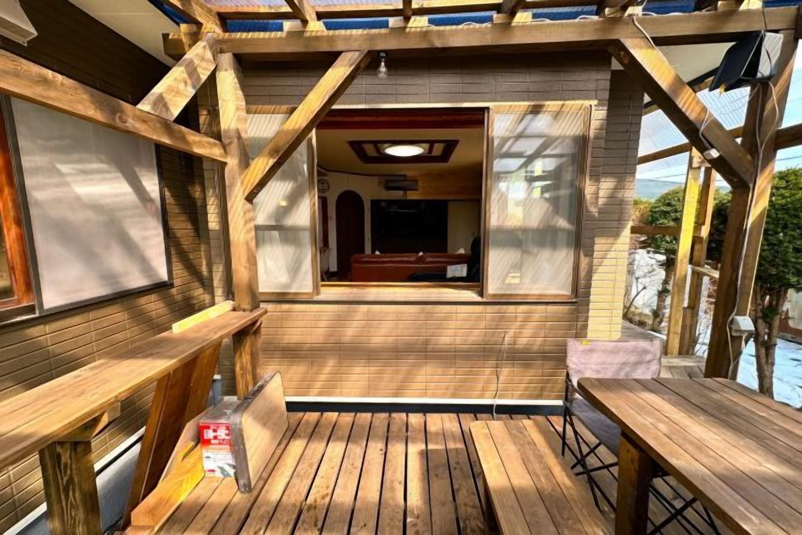 A wooden deck with a view of a pool and a covered seating area.