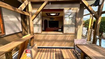 A wooden deck with a view of a pool and a covered seating area.