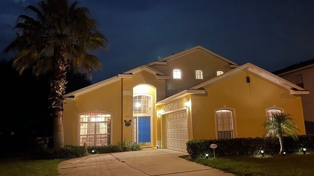 A two-story house with a garage, a front porch, and a well-lit entrance. - Lakeside Villa 5 Bedroom Home (Davenport)