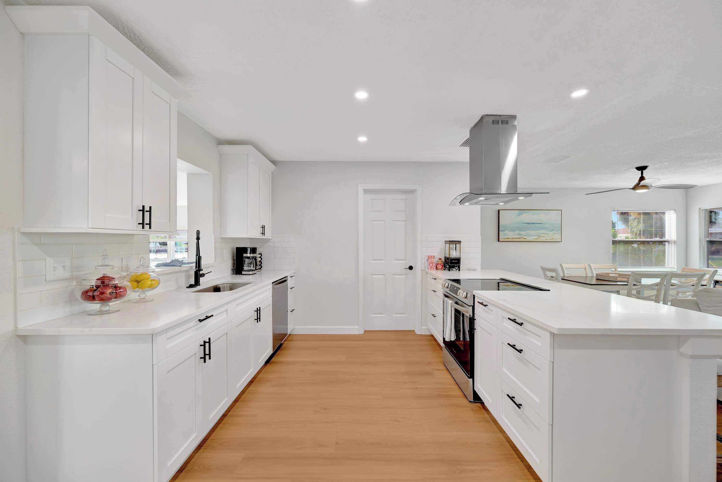 Une cuisine moderne avec des meubles blancs, un îlot central et un four encastré.