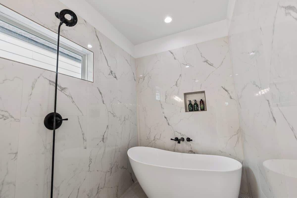 A modern bathroom with a freestanding bathtub, a showerhead, and a small shelf with toiletries.