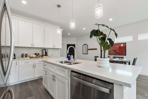 A modern kitchen with white cabinets, stainless steel appliances, and pendant lighting. - Modern 3BR Family Retreat in Downtown Houston (Houston)