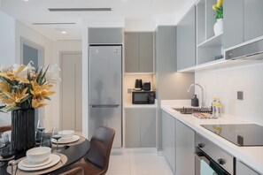 Une cuisine moderne équipée d’un four à micro-ondes encastré, d’un réfrigérateur et d’un plan de travail avec un évier et une machine à café.