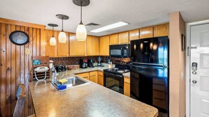 A kitchen with wooden cabinets, a stainless steel refrigerator, a microwave, a stove, and pendant lights. - Mountain Top View in Gatlinburg (Gatlinburg)