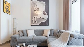 A modern living room with a grey sectional sofa, a marble coffee table, and a wall-mounted abstract art piece. - Dubai Creek Harbour Sleeps 4 With Private Balcony (Dubai)