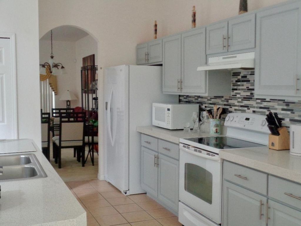 A kitchen with light grey cabinets, a white refrigerator, a microwave, a stove, and a dishwasher.