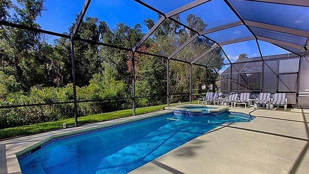 A swimming pool with a covered area, surrounded by lounge chairs and a greenhouse structure.