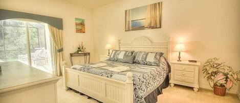 A bedroom with a bed, nightstands, a ceiling fan, a window with curtains, and a painting on the wall.