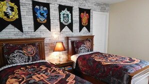 Un dormitorio con dos camas, cada una cubierta con una colcha con motivos de Harry Potter. Hay cuatro pancartas de Harry Potter en la pared sobre las camas.