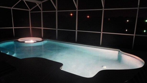 Una piscina con borde curvo, rodeada por una zona cubierta con estructura de celosía.