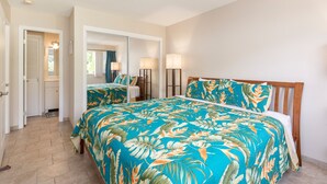 A bedroom with a bed, a mirror, and a nightstand. - Kona Coffee Villas E246 2 Bedroom Condo (Holualoa)