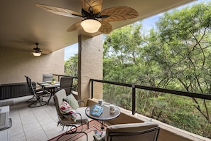 A balcony with a table, chairs, and a ceiling fan. - Kona Pacific D526 1 Bedroom Condo (Kailua-Kona)