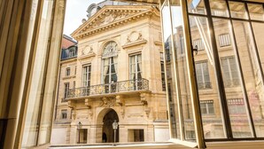 Un bâtiment historique à l’architecture riche et élaborée, doté de grandes fenêtres et d’un balcon orné de balustrades décoratives.
