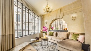 Un salon moderne avec une grande fenêtre, un canapé, un banc, une table basse et un lustre.