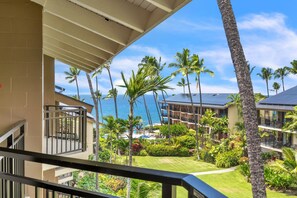 A hotel with a balcony overlooking a pool area, palm trees, and a view of the ocean. - Kona Makai 3305 2 Bedroom Condo (Kailua-Kona)