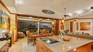 A spacious kitchen with a large island, wooden cabinetry, and a dining area with wicker furniture.