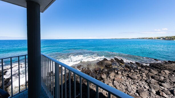 A balcony with a view of the ocean and rocky shoreline. - Alii Villas #232 2 Bedroom Condo (Kailua-Kona)