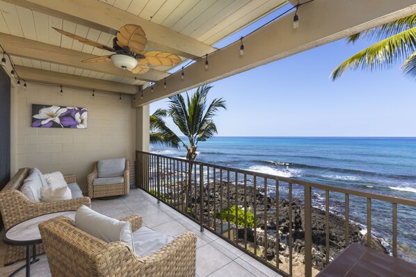 A balcony with wicker furniture, a ceiling fan, and a view of the ocean. - Kona Bali Kai #305 2 Bedroom Condo (Kailua-Kona)