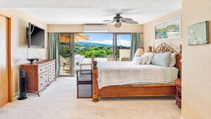 Un dormitorio con cama, cómoda, televisor y balcón con vistas.