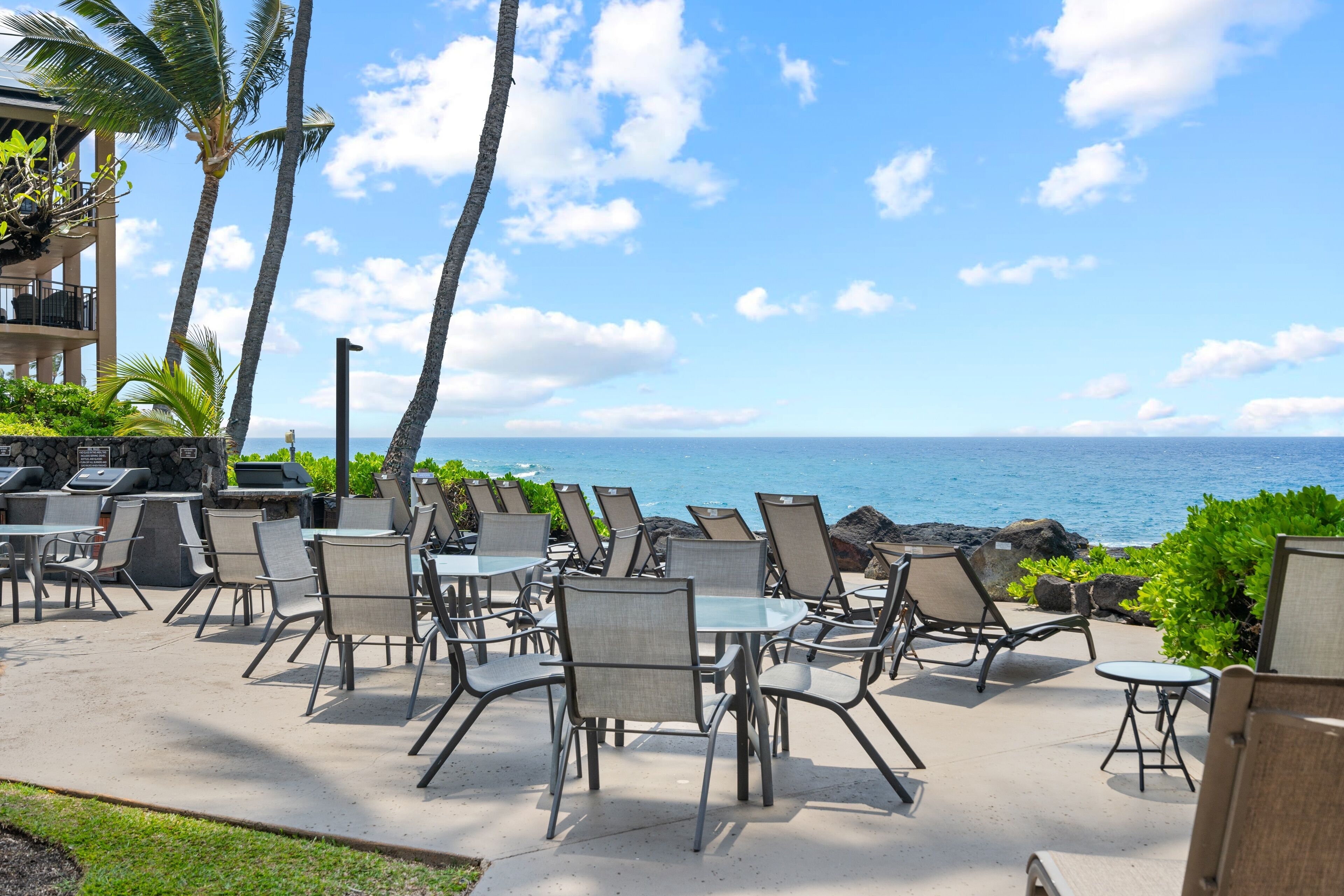 An outdoor seating area with chairs and tables, overlooking a body of water.