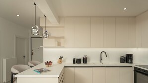 Una cocina moderna con una isla central, muebles blancos y un grifo negro.