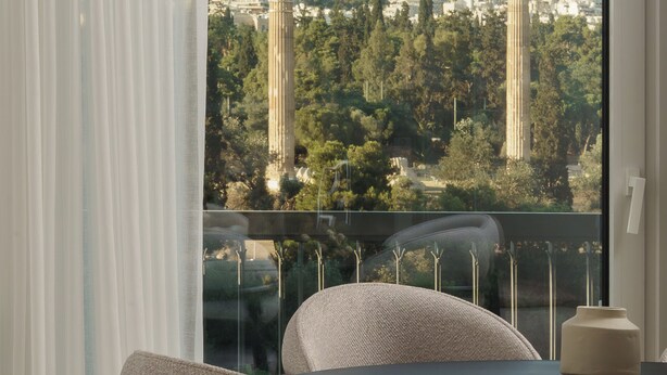 Una habitación moderna con vistas a un paisaje urbano, incluyendo una colina con edificios y una estructura alta.