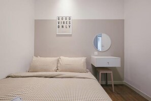 Un dormitorio con cama, mesita de noche, espejo y cartel en la pared.