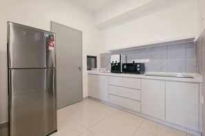 Una cocina moderna con refrigerador de acero inoxidable, gabinetes blancos y una cafetera.