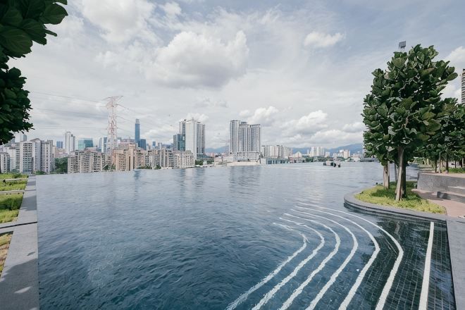 A large, curved infinity pool with a city skyline in the background.
