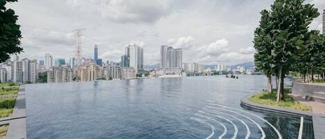 A large, curved infinity pool with a city skyline in the background.