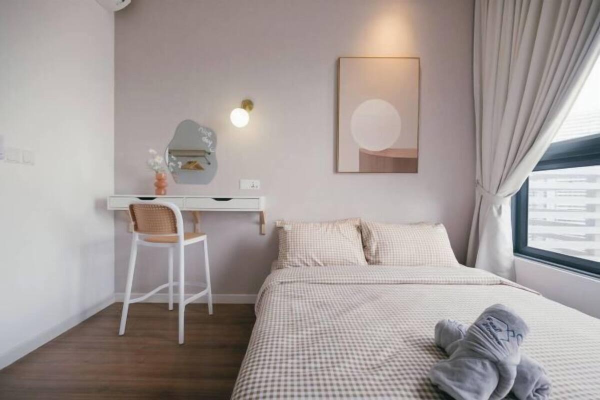 A bedroom with a bed, a desk, a chair, a wall-mounted mirror, and a window with curtains.