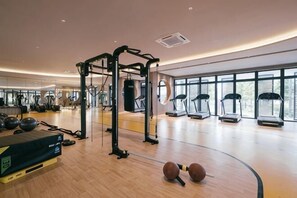 Un gimnasio con equipamiento de ejercicio, cintas de correr y un espejo grande.