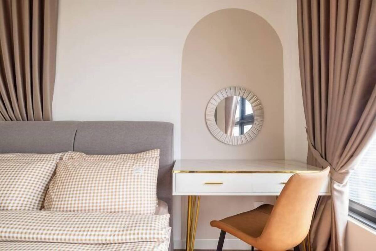A bedroom with a bed, a desk, a chair, and a mirror.