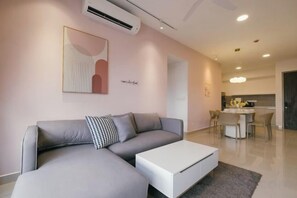 A modern living room with a sectional sofa, a white coffee table, and a kitchen in the background. - M Vertica Tower A Tower A by FEEL HOME (Kuala Lumpur)