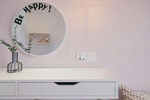 A white vanity with a round mirror, a small plant, and a wall-mounted light switch. - M Vertica Tower A Tower A by FEEL HOME (Kuala Lumpur)