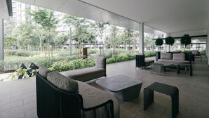 A modern outdoor lounge area with seating, a view of greenery, and a tiled floor. - M Vertica Tower A Tower A by FEEL HOME (Kuala Lumpur)