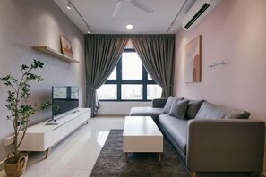 Una sala de estar moderna con un sofá, una mesa de centro, un televisor sobre un mueble bajo, una planta en maceta y un ventanal con cortinas.