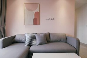 Una sala de estar moderna con un sofá gris, un cojín estampado y una obra de arte minimalista en la pared.