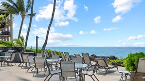 Un espace extérieur aménagé avec des chaises et des tables, offrant une vue sur un plan d’eau.